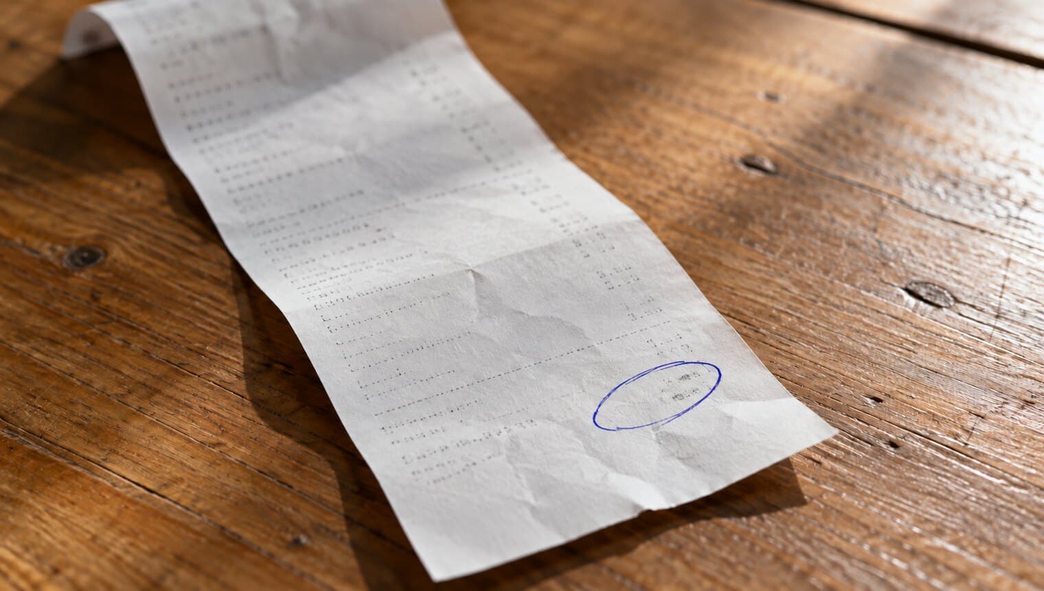 A paper receipt on a table with a small amount circled in pen near the bottom